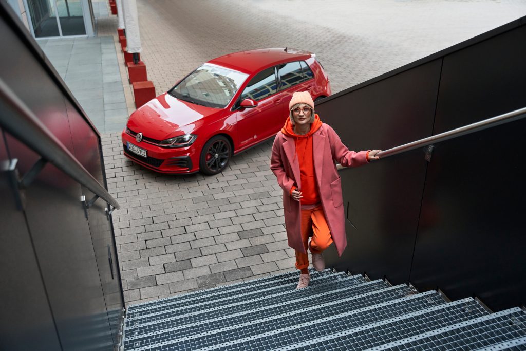 Golf rojo VW con mujer subiendo escaleras